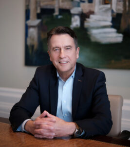 Reiner Lomb, Autor des Buches ASPIRE - Führen mit Emotionen sitzt freundlich lächelnd an einem Tisch.