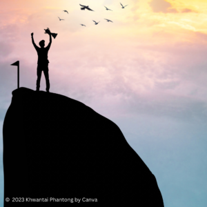 Foto von einem Menschen in Silhouette, der auf dem Gipfel eines Berges die Arme zum Himmel reckt: Erfolg nach langem Aufstieg - wie beim Inspirited Leadership Training